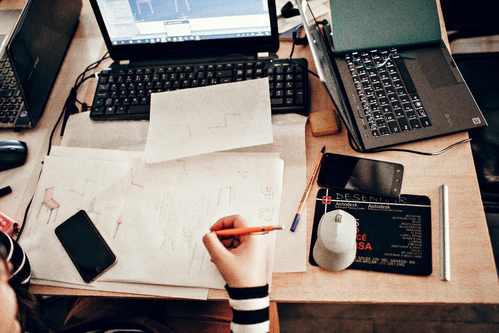 Cluttered creative desk with laptops and sketches, showing the design and strategy work behind digital marketing.