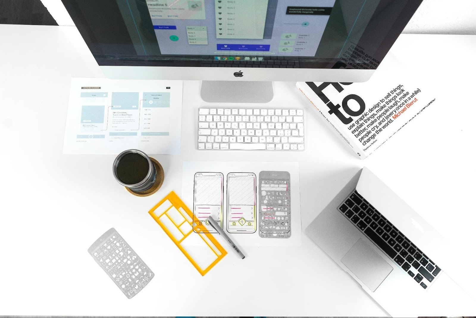 Top-down view of a designer's workspace with wireframe sketches and a graphic design book, emphasizing the value of professional web design.